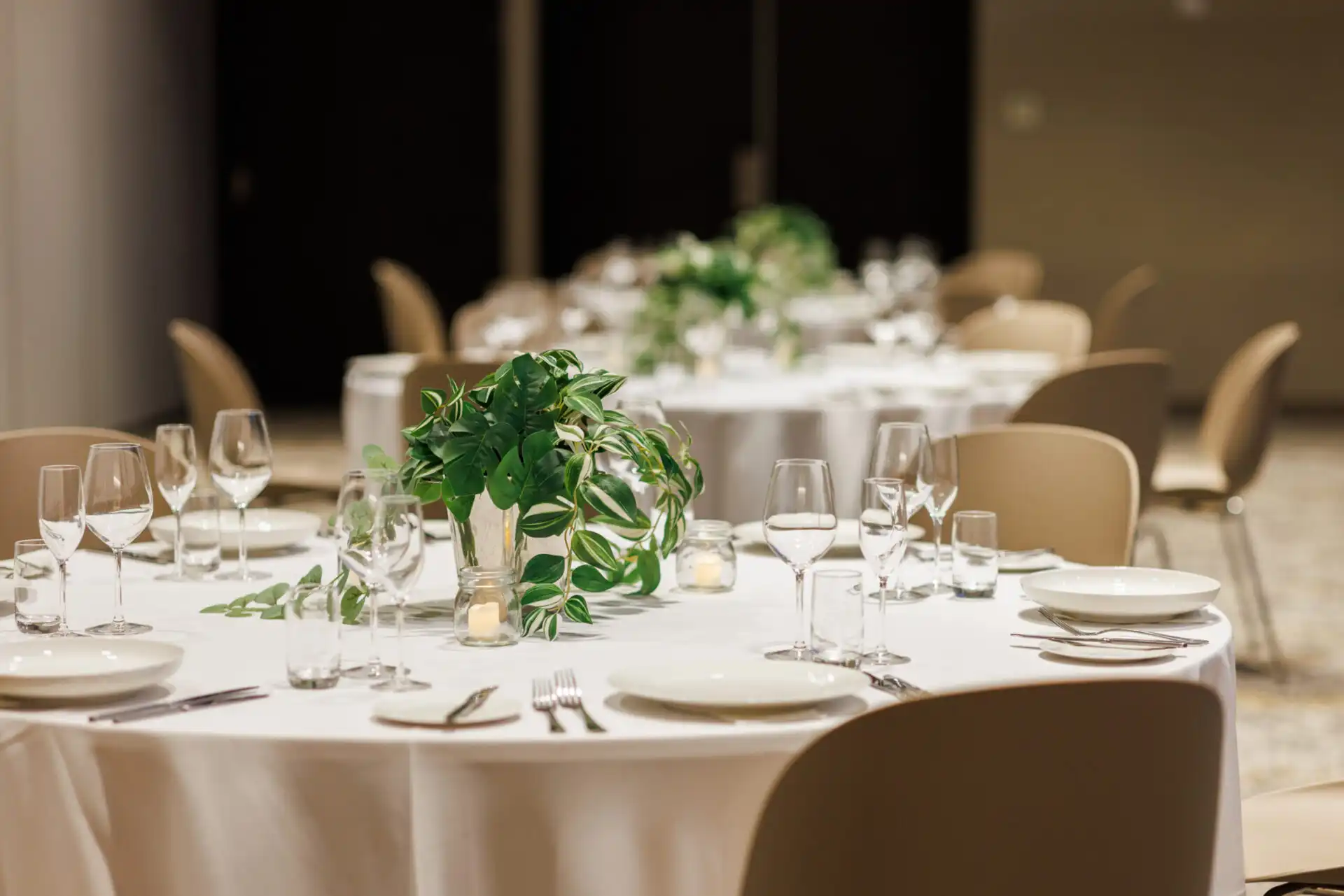 Round tables set for a function at The Maali with floral centrepieces and place settings.